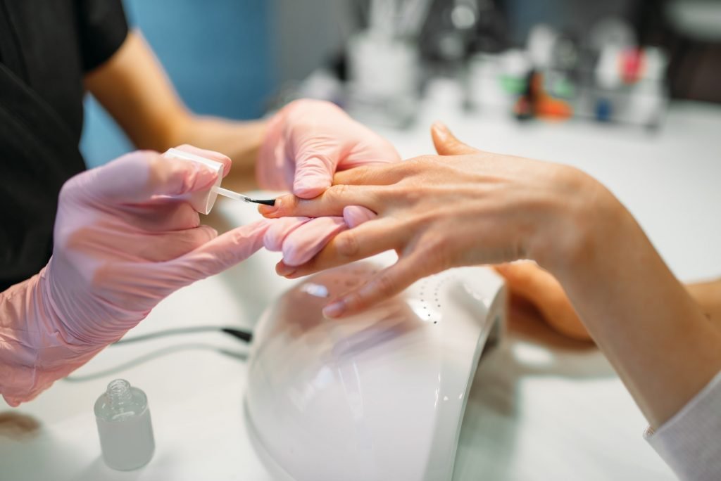 Manicure master applying nail varnish